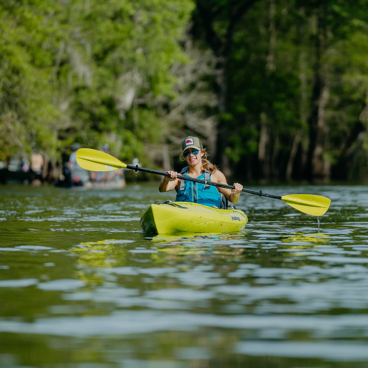 woman paddling towards the camera with the Sunrise Glass in green