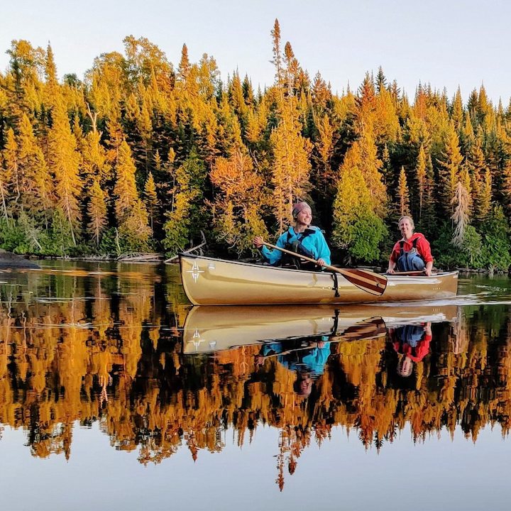 two canoeists on a calm lake in the fall