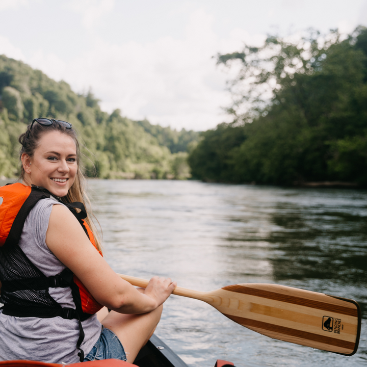 Girl with Arrow wooden canoe paddle turning towards the stern for a photo