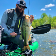 jameson redding with the angler ace across his lap holding fish over edge of kayak