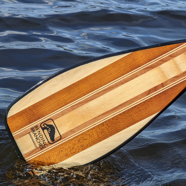 Expedition Plus wooden canoe paddle coming out of the water close-up