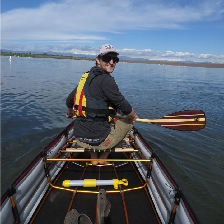 Male bow paddler smiles towards the camera (stern) holding the Viper canoe paddle across his lap