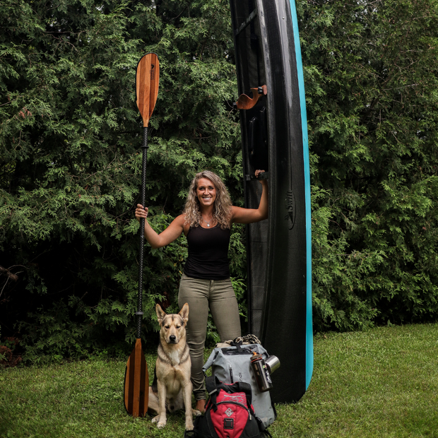 @AlexisOutdoors standing with Navigator paddle, kayak, gear, and dog