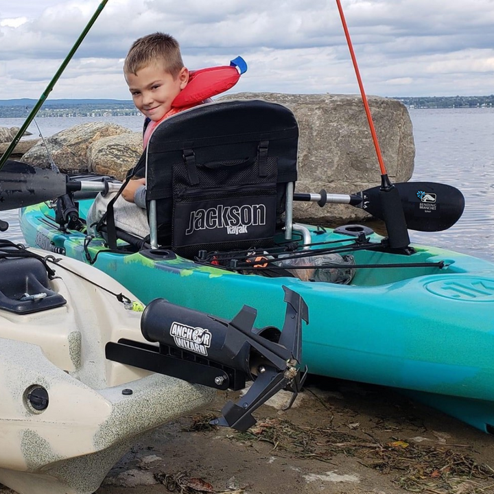 young boy sitting in kayak with Splash across his lap turned around smiling