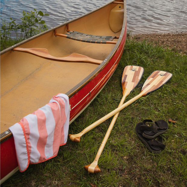 2 canoe paddles laying on the ground next to canoe
