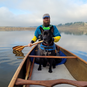 Male stern paddler using the Viper wooden canoe paddle with black dog sitting in front of him